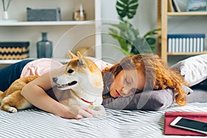 Beautiful young lady sleeping on couch at home hugging adorable puppy