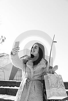 A beautiful young lady takes a selfie photo while shopping. Black and white photo.