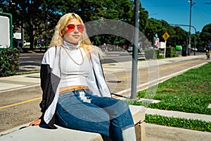 Beautiful young Latin woman in a white t-shirt sitting on a bench in a public park