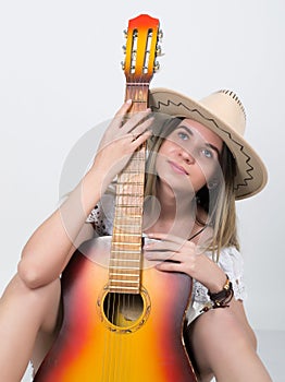 Beautiful young leggy blond Country girl in a litl white dress and cowboy hat with a guitar