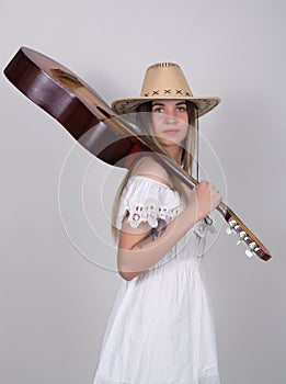 Beautiful young leggy blond Country girl in a litl white dress and cowboy hat with a guitar