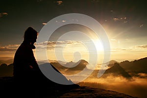 Beautiful young long hair girl tourist enjoy daybreak on the sharp corner of sandstone rock and watch over valley to Sun.