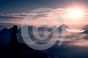 Beautiful young long hair girl tourist enjoy daybreak on the sharp corner of sandstone rock and watch over valley to Sun.