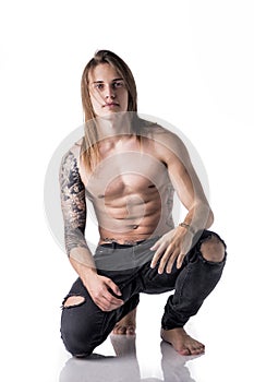 Beautiful young long haired man shirtless, kneeling on the floor