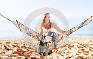 Beautiful young longhaired woman sitting in hammock on the sea side