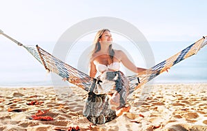 Beautiful young longhaired woman sitting in hammock on the sea side photo