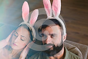 Beautiful young loving couple dreaming together with pink rabbit ears on head. Happy family preparing for Easter.