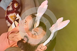 Beautiful young loving couple dreaming together with pink rabbit ears on head. Happy family preparing for Easter.