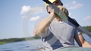 Beautiful young man kayaking on lake. Boy rowing oars on a kayak on the river. Sports hike, water rafting in nature