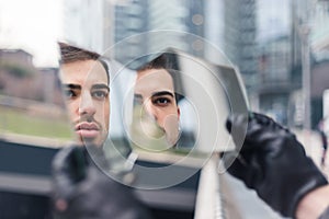 Beautiful young man looking at himself in a shattered mirror