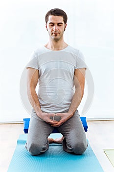 Beautiful young man practicing yoga at home. Vajrasana pose.
