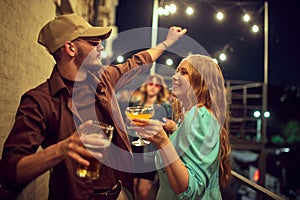 Beautiful young man and woman, couple, friends spending good time together in evening outdoors. Dancing and drinking