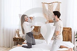 Beautiful young man and woman fight pillows