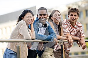 Beautiful young men and women smiling and looking at camera leaning on a balcony. Diverse group of cheerful and hopeful