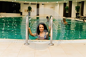 Beautiful young mixed race African American woman, wearing bikini and relaxing on a swimming pool
