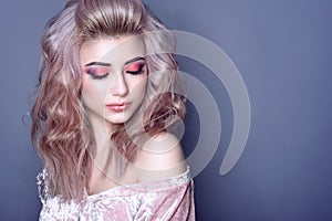 Beautiful young model with colorful artistic make up and wavy hairstyle looking down