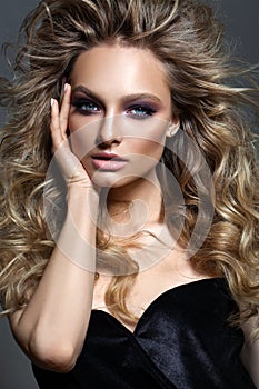 Beautiful young model with fashion make up, perfect skin, healthy hair, nude lips and fingers near the face.