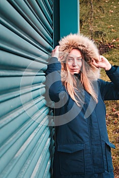 Beautiful young model posing in blue hooded coat with artifical fur