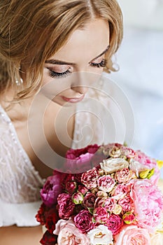 Beautiful young model woman with closed eyes and with sexy full lips in stylish peignoir holding bouquet of roses and
