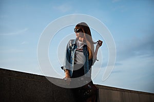 Beautiful and young model woman with perfect body in jeans jacket and in the fashionable t-shirt posing with blue summer