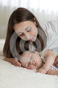 Beautiful young mom and baby sleeping in bed at home