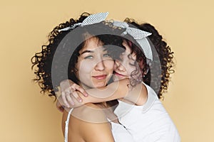 Beautiful young mom and daughter standing huging cheek to cheek.