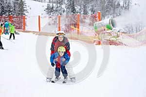 Beautiful young mom and her toddler boy, skiing in the mountains