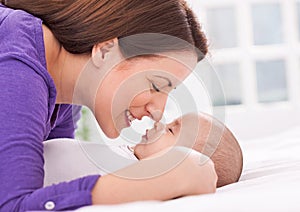 Beautiful young mother and baby are gently touching noses