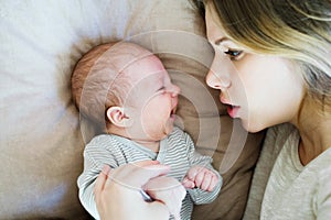 Beautiful young mother with baby son lying on bed