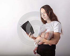 Beautiful young mother breastfeeding a baby while reading a black book
