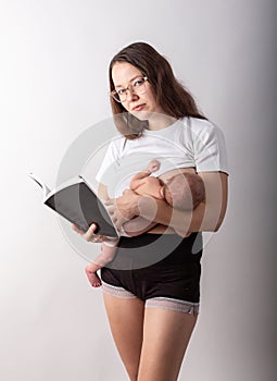 Beautiful young mother breastfeeding a baby while reading a black book