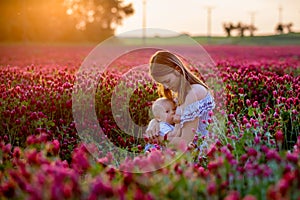 Beautiful young mother, breastfeeding her toddler baby boy in go