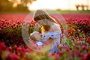 Beautiful young mother, breastfeeding her toddler baby boy in go