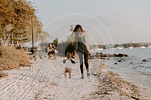 Beautiful Young Mother and Cute Little Boy Son Walking and Enjoying the Nice Outdoor Weather on the Sandy Beach next to the Ocean