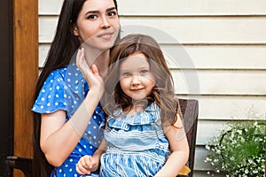 Beautiful young mother with cute little daughter relaxing in garden