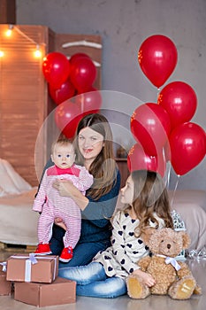 Beautiful young mother and daughter in dresses with wreathes on their hads with colorful baloons in photo studio