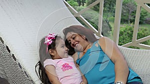 Beautiful young mother and daughter laying and relaxing together on a hammock