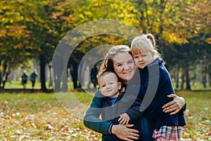 Beautiful young mother with daughter and son are walking in the autumn park. close-up portrait