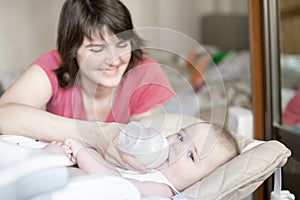 Beautiful young mother feeding her baby from bottle