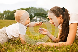 Beautiful young mother giving flower to her baby