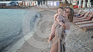 Beautiful young mother is having fun with her cute daughter on the beach in autumn or spring.