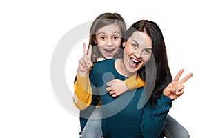 Beautiful young mother and her daughter making peace sign hand gesture, laughing and looking at camera. Isolated over white.