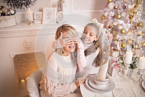 Beautiful young mother with her daughter in the New Year`s interior at the table near the Christmas tree.