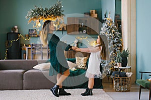 Beautiful young mother and her little daughter having fun at home for Christmas time