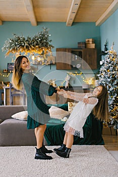 Beautiful young mother and her little daughter having fun at home for Christmas time