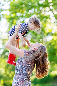 Beautiful young mother holding her happy little kid girl in arms