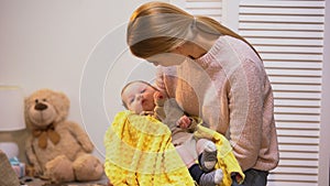 Beautiful young mother holding little baby son in arms, newborn love and care