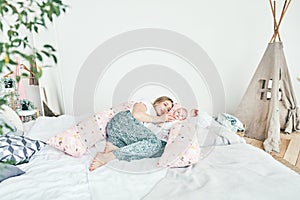 A beautiful young mother with long blonde hair and a daughter of 2-3 months are resting on the bed in the bedroom