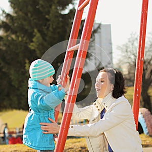 Beautiful young mother playing with her baby on the playground