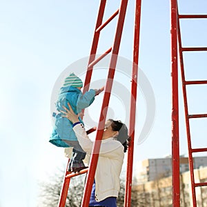 Beautiful young mother playing with her baby on the playground